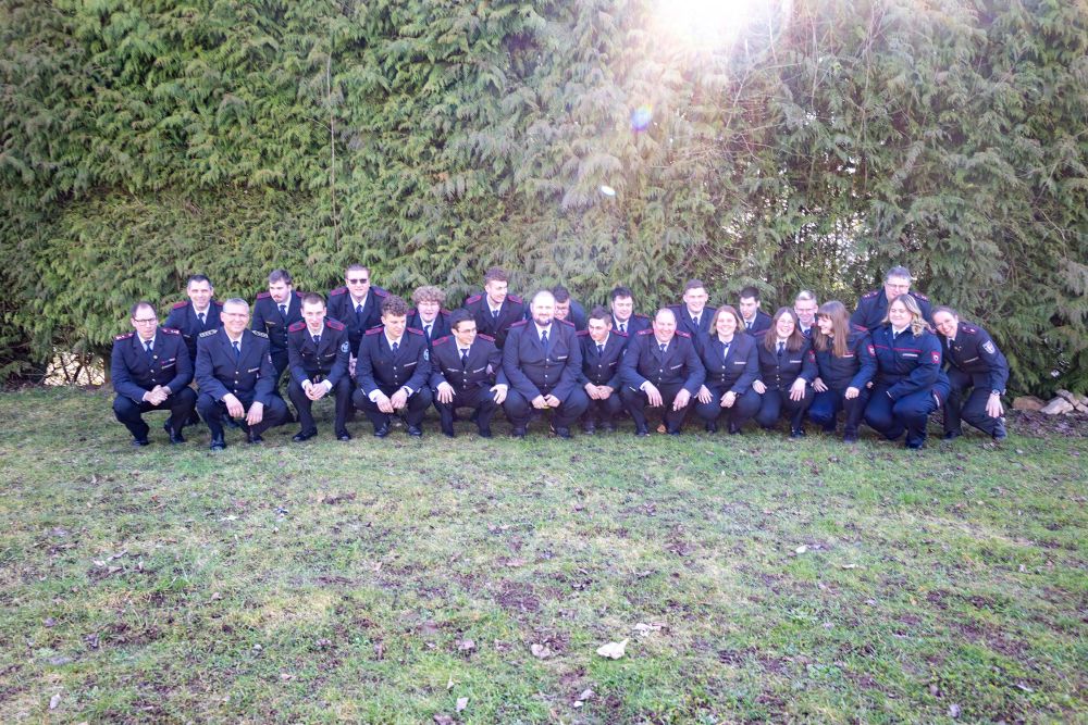 Gruppenbild in der Hocke vor einer grünen Hecke